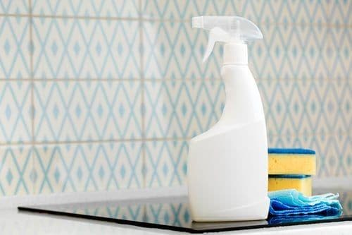 Spray bottle and cloths on a tiled bathroom surface prepared for disinfection