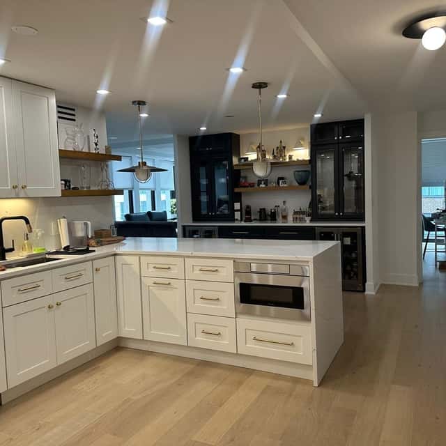 Bright open-plan kitchen with white shaker cabinets, a dark glass display cabinet and light oak floors after cleaning — Ferrer Cleaning, Chicago, IL