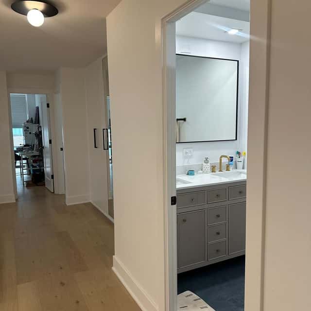 Hallway leading to a cleaned bathroom with a grey vanity and a framed mirror — Ferrer Cleaning, Chicago, IL