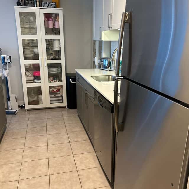 Galley kitchen with a glass-front pantry cabinet, stainless refrigerator and cleaned tile floor — Ferrer Cleaning, Chicago, IL