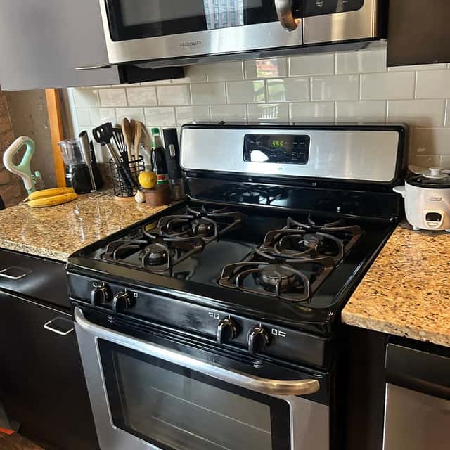 Black gas range with a granite counter and a cleaned tile backsplash — Ferrer Cleaning, Chicago, IL